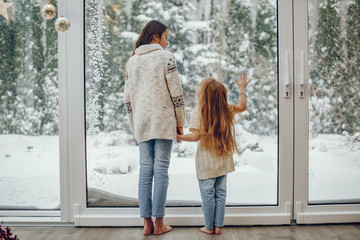 Cute childrens at home. Kids in a Christmas decorations. Sisters in a cute sweaters.