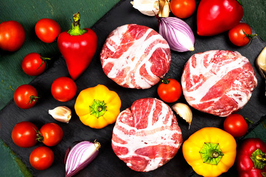 Meat raw round cutlets wrapped in bacon and vegetables onion, sweet pepper, garlic on a black stone background. The ingredients for the burgers. The view from the top. The concept of meat-lovers - Powered by Adobe