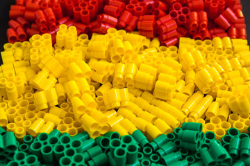 Fototapeta premium Plastic bricks of red, yellow and green. Details of toys. Close up. Place for text or advertising