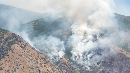 Pano frame Nature landscape with puffs of white smoke rising from mountain forest fire