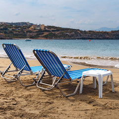 two sun loungers on the sandy beach of the Greek resort town of Agios Nikolaos