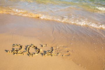 2020 summer beach holiday season written on golden sand - new season lettering on sand - numbers 2020 year  travel vacation - washed away