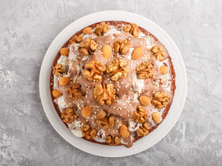 Homemade cake with milk cream, cocoa, almond, hazelnut on a gray concrete  background with orange textile. Top view.