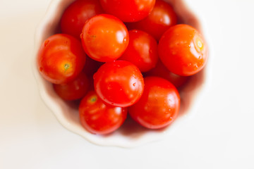 lots of cherry tomatoes in a white plate on a white background. texture. concept of fresh vegetables and healthy food. space for text. top view of tomatoes. ripe harvest.