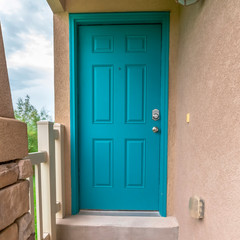 Square Close up of home entrance with blue green front door and concrete exterior wall