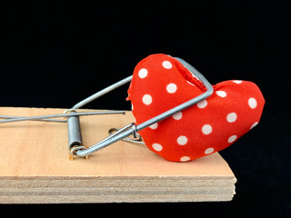 Heart in a mousetrap on a black background. A trap with a heart, Love is like a bait. Valentine's Day, Love Day