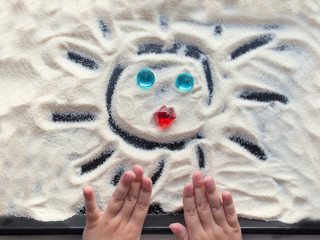 Сhild draws on the sand. Creativity with a small child. Drawing on the sand.