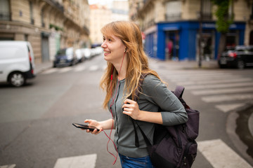 Fototapeta premium young woman crossing the street listening to music with mobile phone and earphones