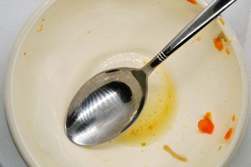 Empty bowl. Dirty, empty bowl with spoon. After meal. Top view. Dirty bowl with food leftovers