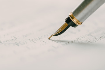 Fototapeta premium Fountain pen on an ancient handwritten letter. Old story. Retro style.