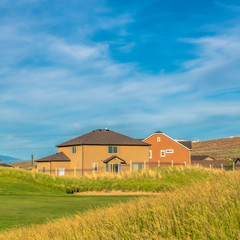Square Green grasses of golf course with houses and mountain in the scenic background