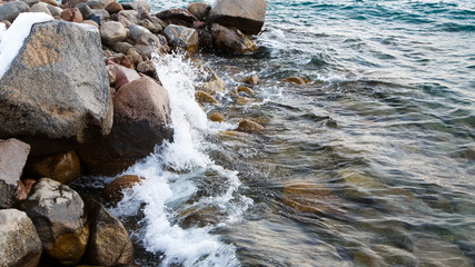 Stones on the sea beach. Pasture winter day. Clear water and sand. Kyrgyzstan, Issyk-Kul Lake