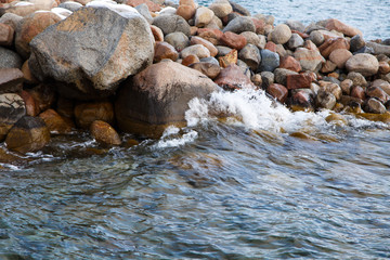 Stones on the sea beach. Pasture winter day. Clear water and sand. Kyrgyzstan, Issyk-Kul Lake