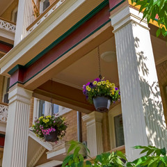 Square Townhomes balconies with columns and lattice railings against trees and sky