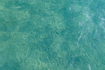 Clear water texture in blue. Background of the ocean and the sea backlit by the sun. Natural water