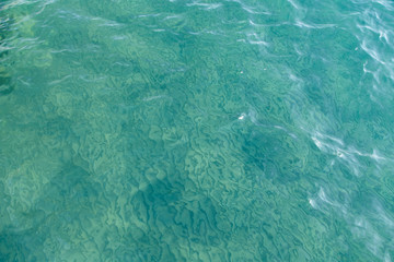 Clear water texture in blue. Background of the ocean and the sea backlit by the sun. Natural water