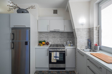 White kitchen set. Home appliances. Window with blinds.