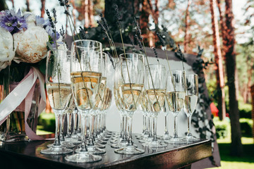 Glasses of with champagne decorated with lavender. Wedding in park. Outdoor decoration