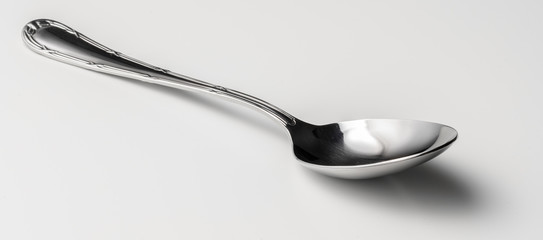 Silver dessert spoon cutlery on grey background