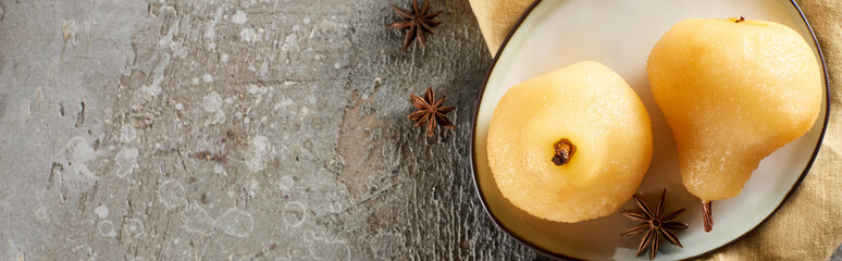 top view of delicious pear in wine with anise served on plate on napkin on grey concrete surface,...