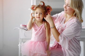 Family sitting in a room. Mother in a pink pajamas. Mom and daughter with curlers on their heads