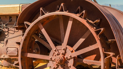 Pano Close up of the damaged wheels of an old vintage tractor against sunny blue sky