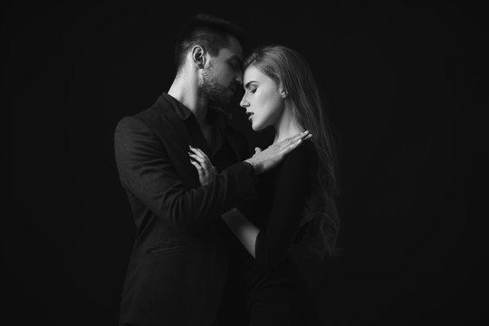 elegant couple in the tender passion. man embracing beautiful woman in black dress. black and white