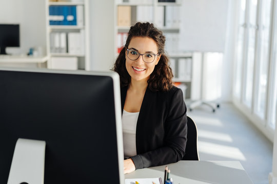 Young businesswoman sitting working at a desktop - Powered by Adobe