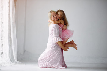 Fototapeta na wymiar Beautiful woman with child. Woman in a pink pajama. Child in a bedroom in a pink dress.