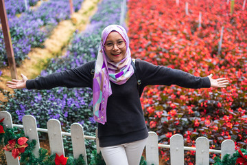 Happy and joyful portrait of young muslim woman in hijab with beautiful colorful flowers park at Cameron Highlands