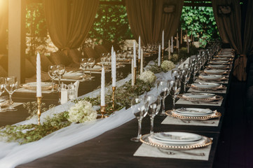 Outdoor wedding and romantic table setting in rustic style on wooden table. Plates, glasses, vintage silverware, blank rough tag and lavender flowers.