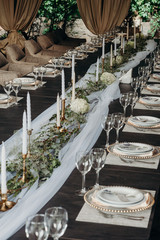 Outdoor wedding and romantic table setting in rustic style on wooden table. Plates, glasses, vintage silverware, blank rough tag and lavender flowers.