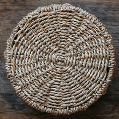 Round wicker basket on a wooden background. Pattern of round texture. Top view. Central composition.