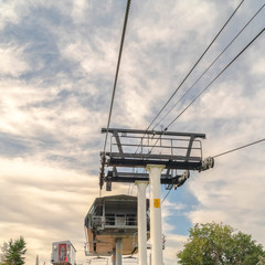 Square Chairlift on top of mountain against cloudy blue summer sky in Park City Utah