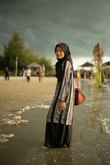 Attractive young Muslim Asian woman in hijab at beach