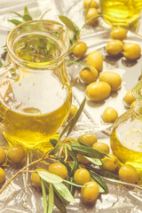 Extra virgin olive oil glass jar and olives on a table.