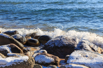Stones on the sea beach. Pasture winter day. Clear water and sand. Kyrgyzstan, Issyk-Kul Lake