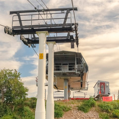 Square frame Chairlift on top of mountain against cloudy blue summer sky in Park City Utah