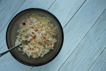 Sauerkraut in a transparent brown bowl with a fork on a white wooden table
