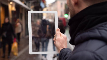 Close up of an young man is using a futuristic latest innovative technology glass tablet for graphic implementation during walking in city center by day.