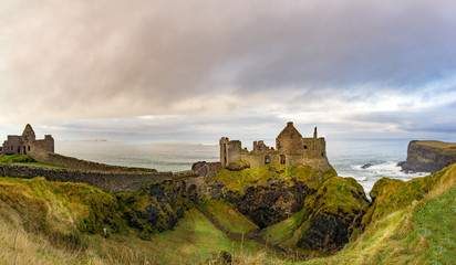 Obraz premium Ruined medieval Dunluce Castle on the cliff dramatic sky. Part of Wild Atlantic Way, Bushmills, County Antrim, Northern Ireland. Filming location of popular TV show, Game of Thrones, Castle Greyjoy