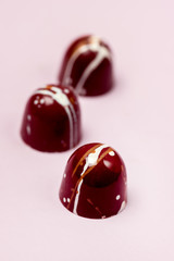 Three Luxury Bonbons Painted with White Colors on Pink background Beautiful and Exclusive Handmade chocolate Candy Vertical
