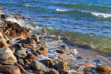 Fototapeta na wymiar Stones on the sea beach. Pasture winter day. Clear water and sand. Kyrgyzstan, Issyk-Kul Lake