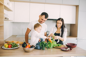 Family in a kitchen. Beautiful mother with little son. Father in a white t-shirt.