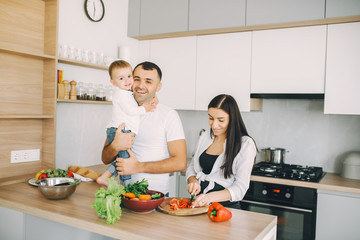 Family in a kitchen. Beautiful mother with little son. Father in a white t-shirt.
