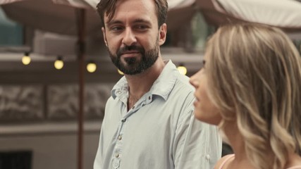 A positive happy couple man and woman are walking by street while talking to each other outdoors in summer - Powered by Adobe