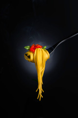 Spaghetti with tomato sauce and basil on a fork, with steam. Close-up shot, shallow focus.