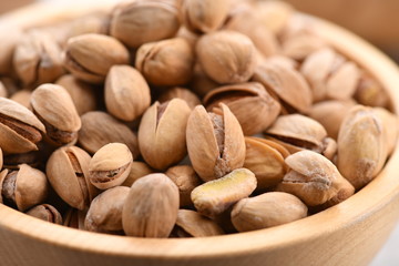 many pistachios in a wooden bowl. Large. Horizontal