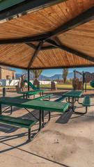 Vertical Empty green tables and benches in an urban park