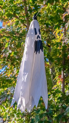 Vertical Hanging ghost halloween outdoor decoration on a sunny day
